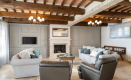 Modern living room with wooden beams, neutral color palette, comfortable sofas, and a cozy fireplace, featuring stylish decor and natural light.