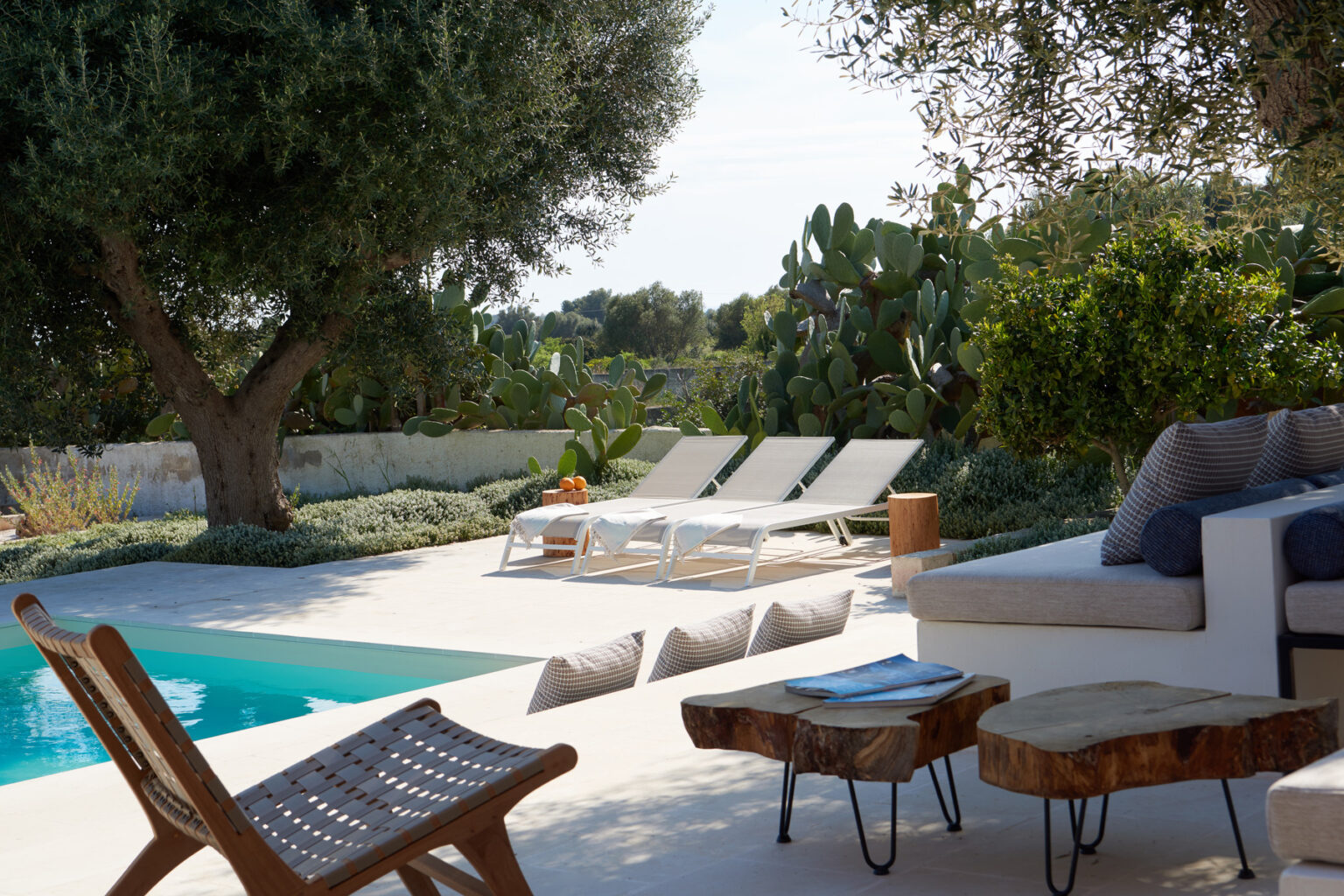 Luxurious outdoor pool area featuring sun loungers, a cozy seating arrangement, and lush greenery, perfect for relaxation and leisure in a serene setting. | Only on SopranoVillas