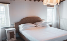 Cozy bedroom featuring a plush bed with white linens, a stylish headboard, and bedside tables. Natural light streams in through the windows, creating a warm and inviting atmosphere. Ideal for relaxation and comfort.