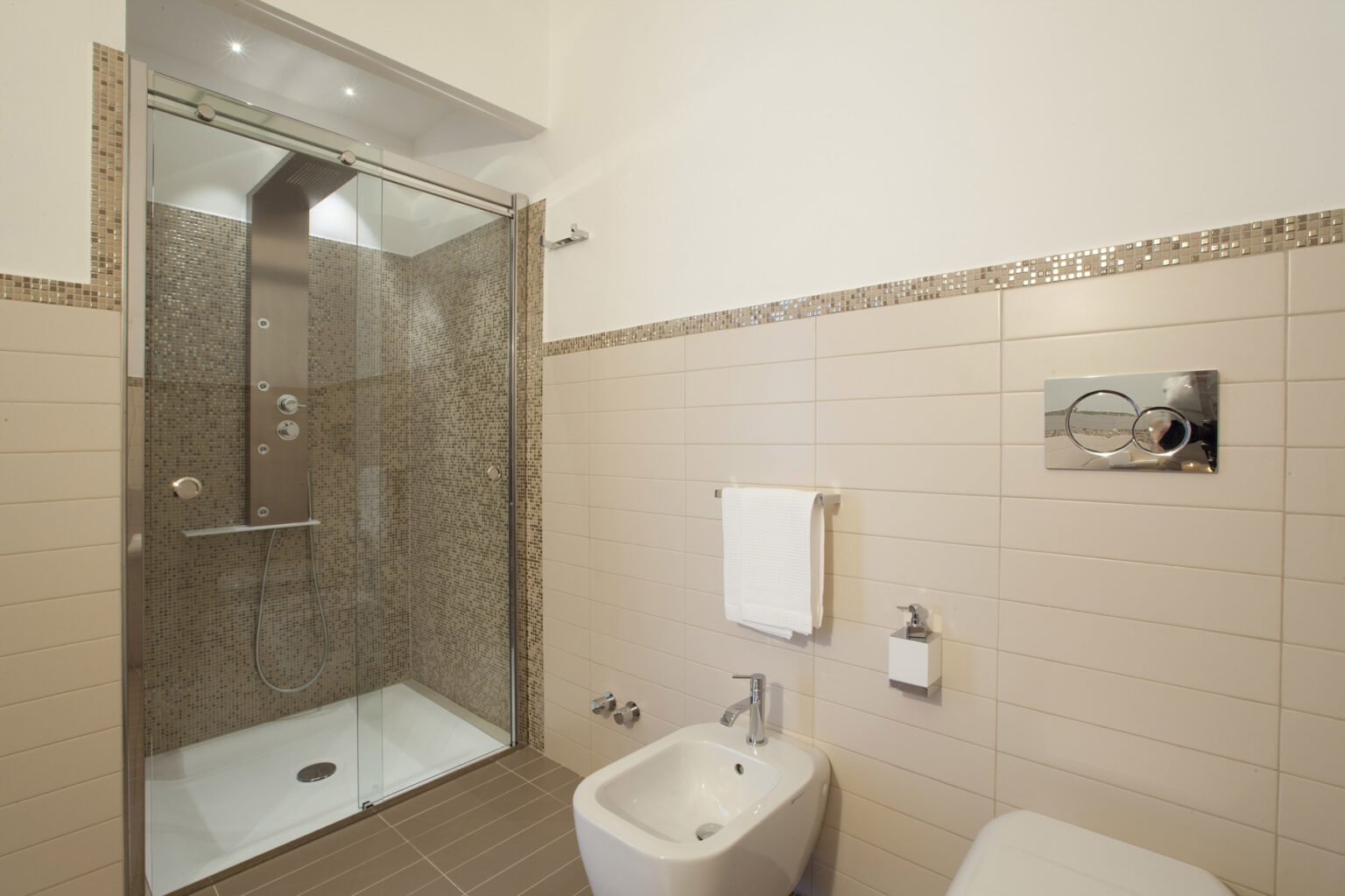 Modern bathroom featuring a glass shower enclosure, tiled walls, a bidet, and elegant fixtures, designed for functionality and style. | Only on SopranoVillas