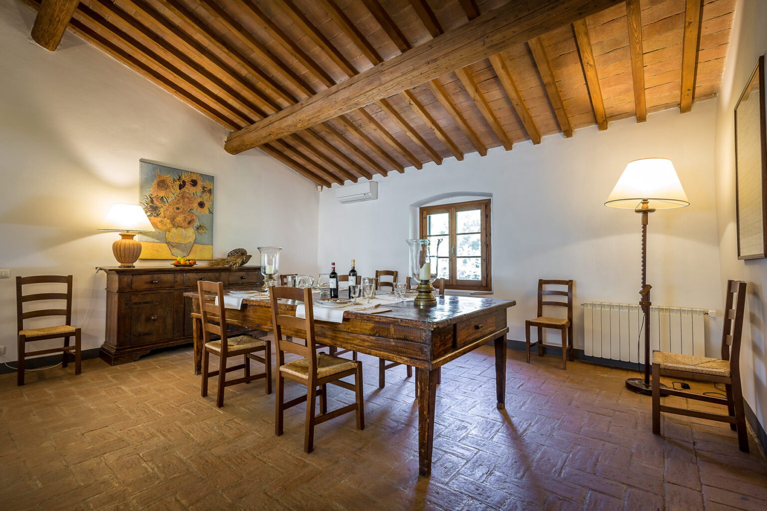 Cozy dining room featuring a wooden table surrounded by chairs, a sideboard, and warm lighting, showcasing rustic decor and exposed beam ceiling. | Only on SopranoVillas