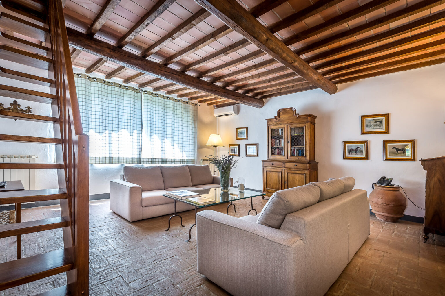 Cozy living room with wooden beams, natural light from large windows, comfortable sofas, a glass coffee table, and decorative artwork on the walls. | Only on SopranoVillas
