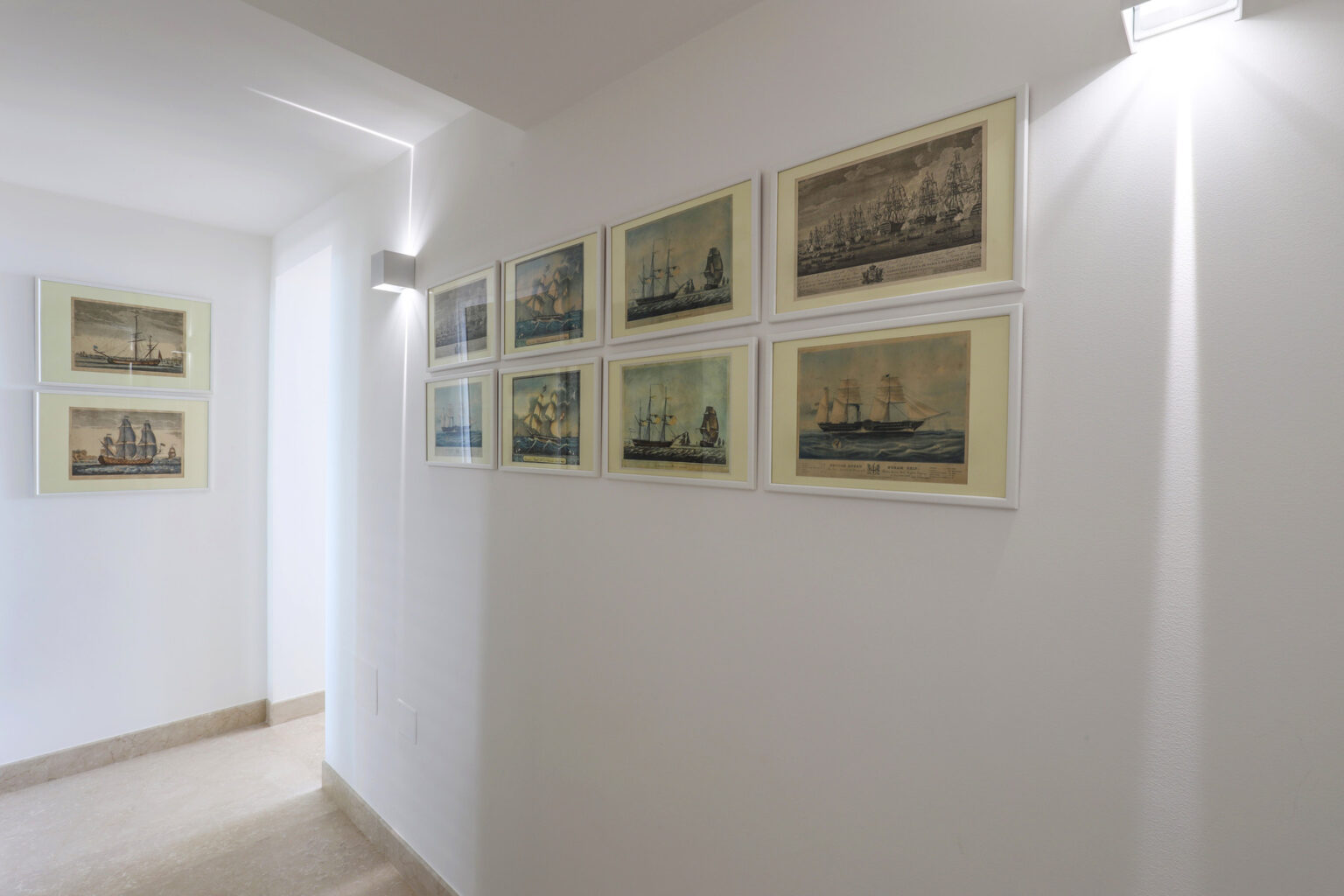 Gallery wall displaying vintage maritime artwork in a well-lit hallway, featuring framed prints of ships and nautical scenes. | Only on SopranoVillas