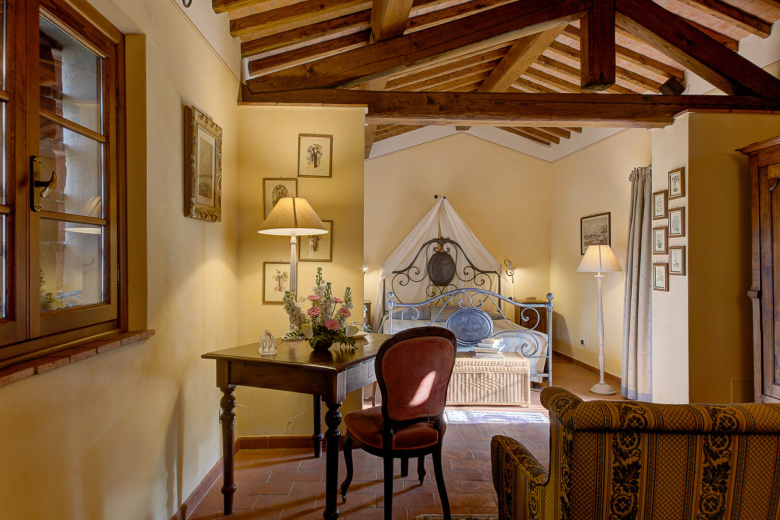 Cozy bedroom interior featuring a wooden ceiling, vintage decor, a comfortable bed with a canopy, a writing desk, and warm lighting, creating an inviting atmosphere. | Only on SopranoVillas