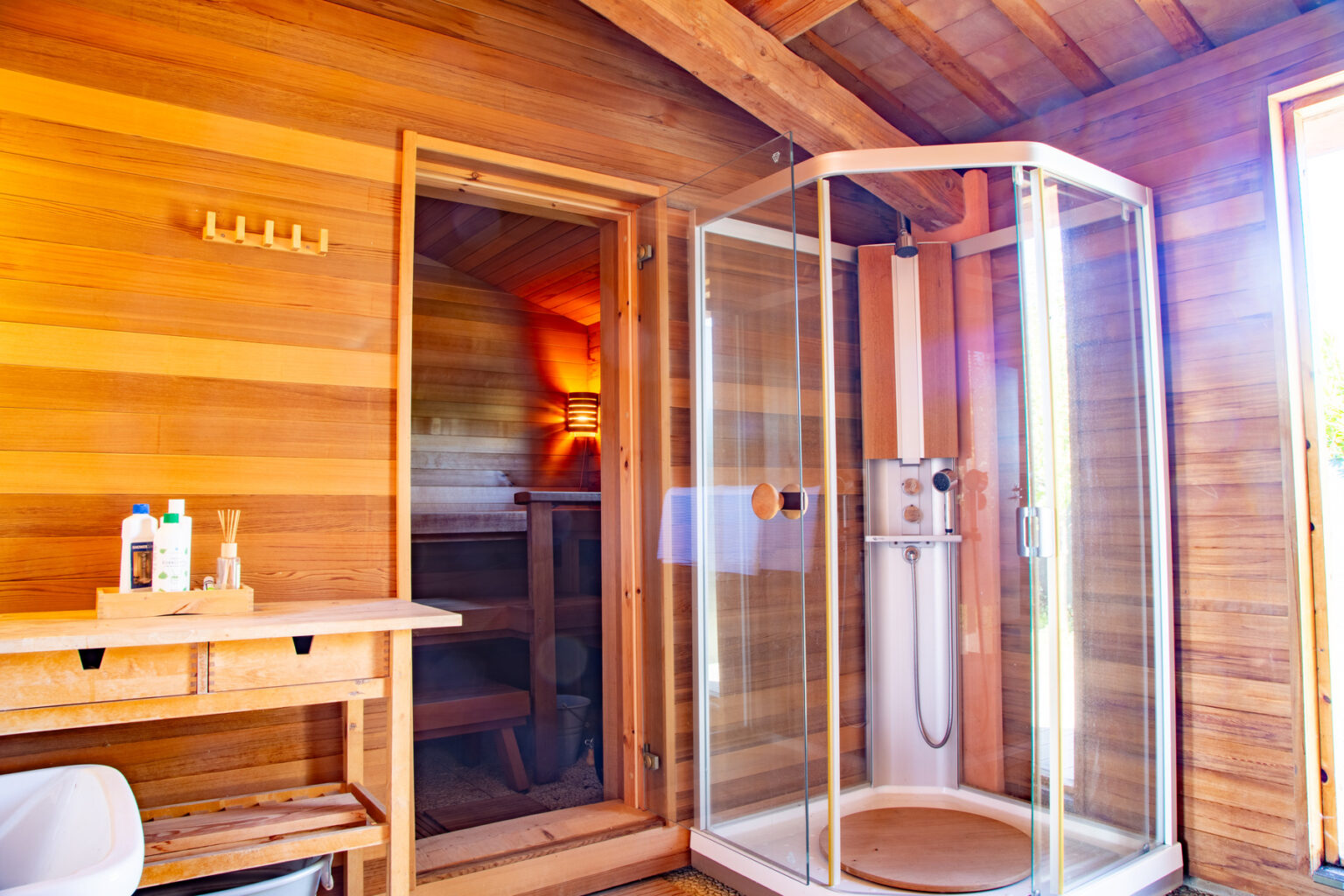 Modern bathroom interior featuring a glass shower enclosure, wooden walls, and a cozy atmosphere with natural light. | Only on SopranoVillas