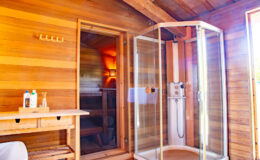 Modern bathroom interior featuring a glass shower enclosure, wooden walls, and a cozy atmosphere with natural light.