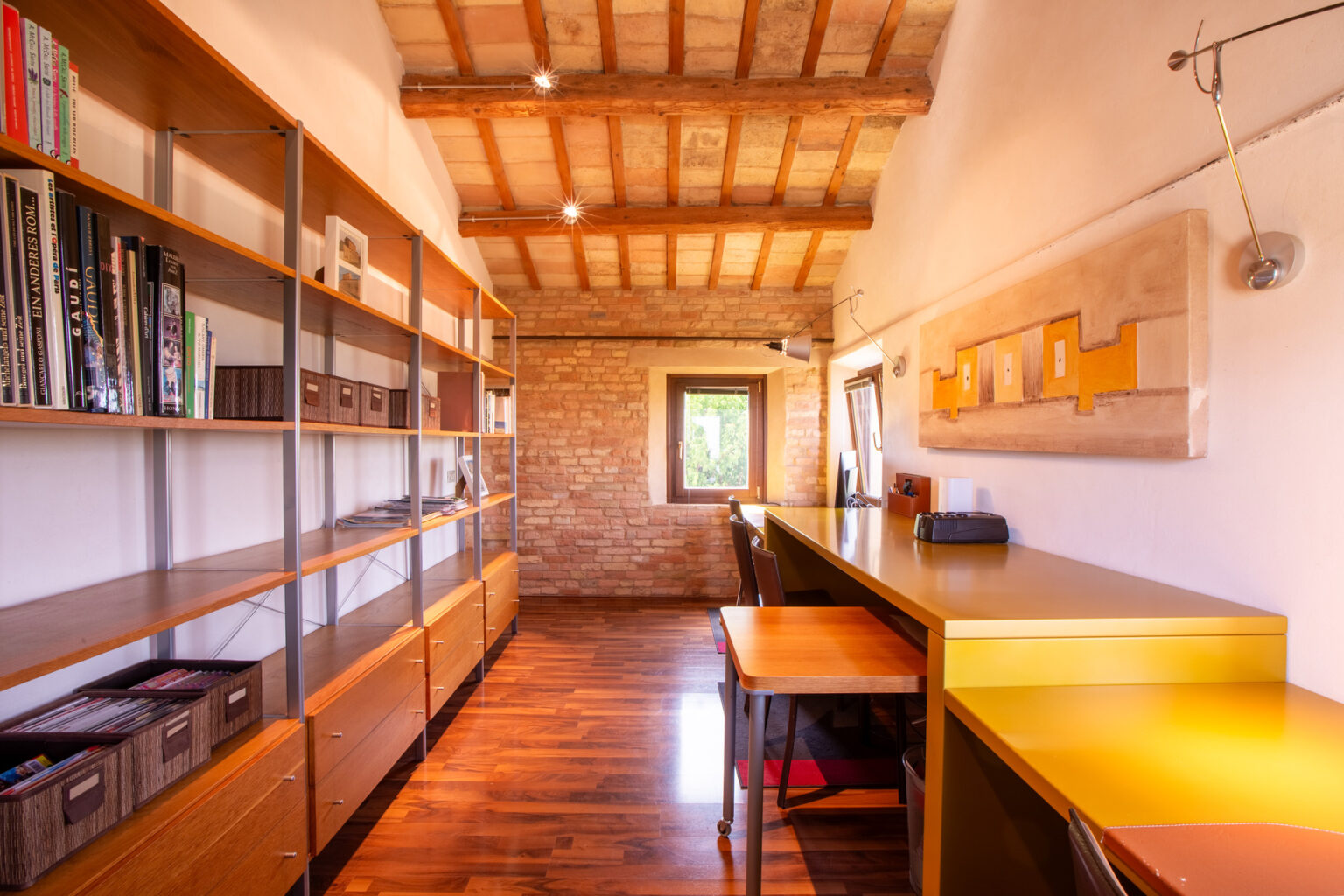 Modern office interior featuring wooden shelves filled with books, a sleek yellow desk, and exposed wooden beams on the ceiling, creating a bright and inviting workspace. | Only on SopranoVillas