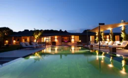Luxurious modern villa with a serene swimming pool surrounded by lounge chairs and illuminated by soft lighting at dusk, showcasing a tranquil outdoor space perfect for relaxation and entertainment.