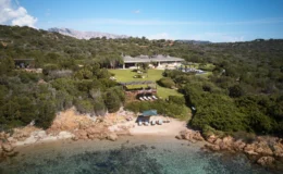 Aerial view of a luxurious beachfront villa surrounded by lush greenery and rocky shoreline, featuring landscaped gardens, outdoor seating areas, and a clear turquoise sea. Ideal for vacation rentals or private getaways in a serene natural setting.