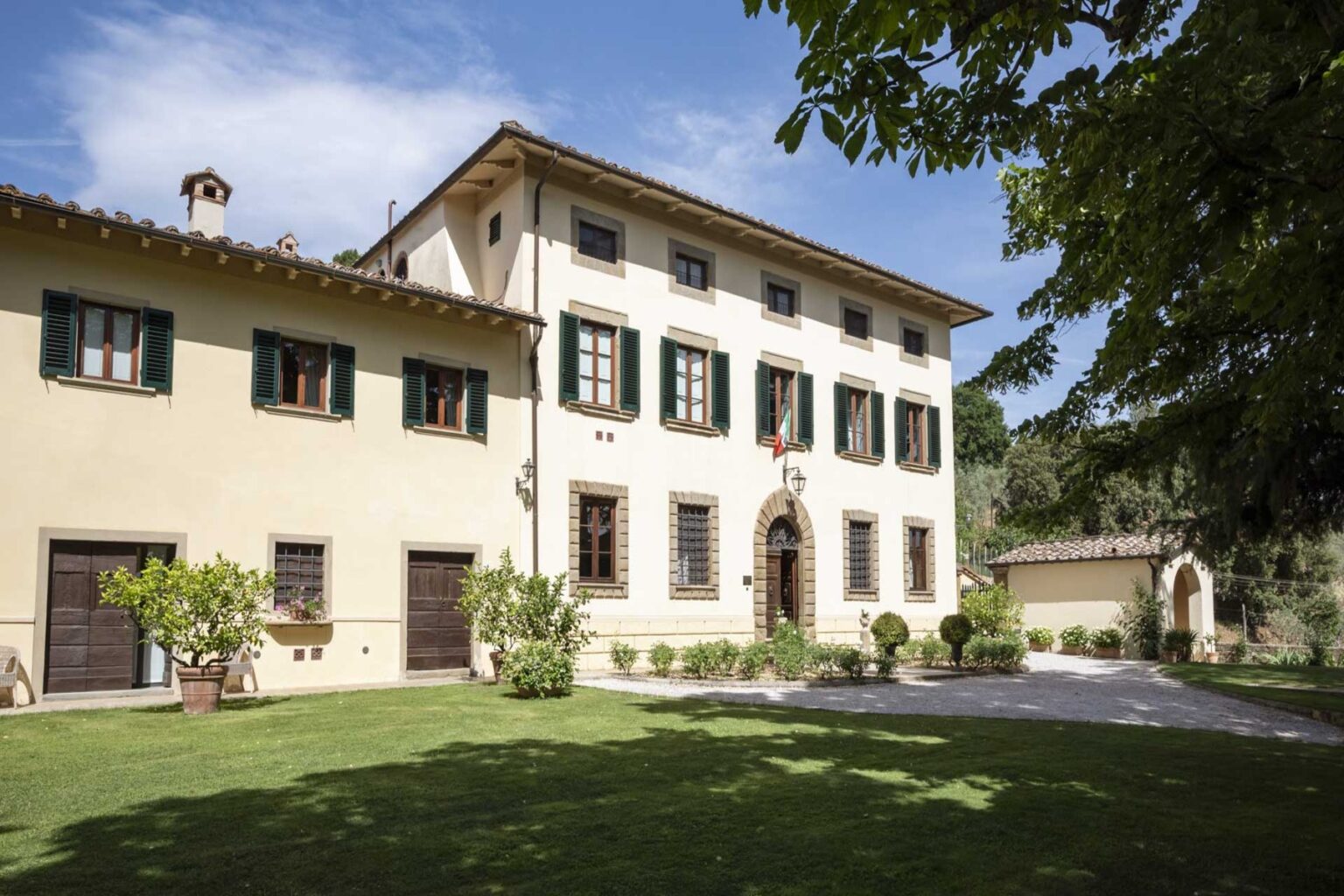 Historic villa with a classic architectural design, surrounded by lush greenery and a well-maintained garden, showcasing large windows and a charming entrance. | Only on SopranoVillas