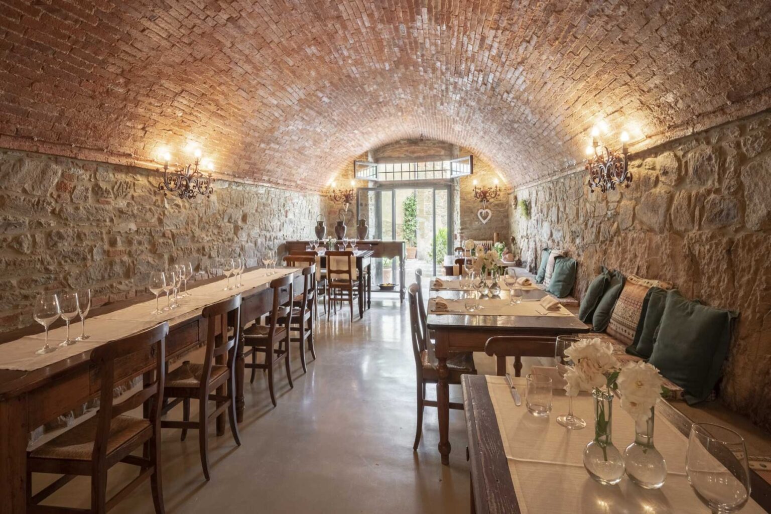 Cozy restaurant interior featuring stone walls and a vaulted brick ceiling, with wooden tables set for dining, elegant glassware, and soft lighting creating a warm ambiance. | Only on SopranoVillas