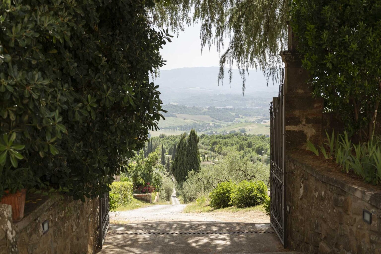 Scenic view through an archway leading to rolling hills and greenery, showcasing a tranquil landscape in the countryside. | Only on SopranoVillas