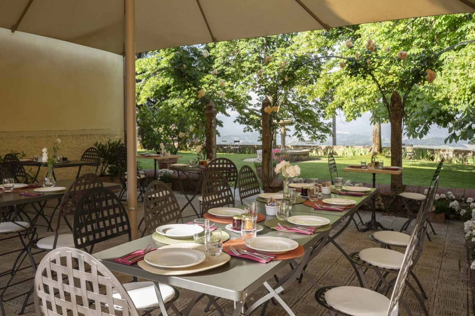 Outdoor dining area set up with tables and chairs under a canopy, surrounded by lush greenery and trees, providing a scenic view for guests. | Only on SopranoVillas