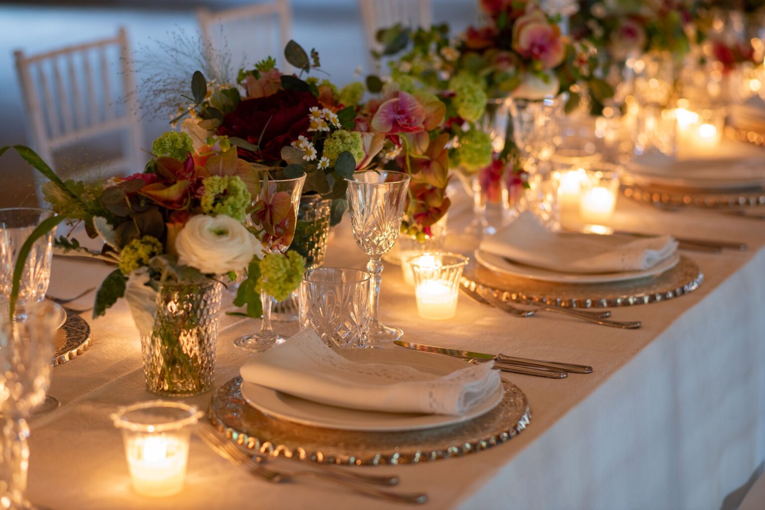 Elegant dining table set for a special occasion, featuring lush floral arrangements, crystal glassware, and soft candlelight, creating a warm and inviting atmosphere. | Only on SopranoVillas
