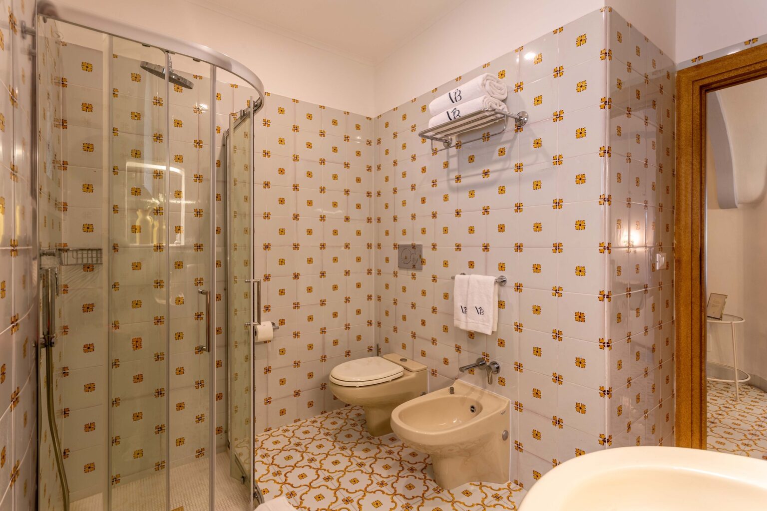 Modern bathroom featuring a glass shower enclosure, bidet, and decorative patterned tiles, creating a stylish and functional space. | Only on SopranoVillas