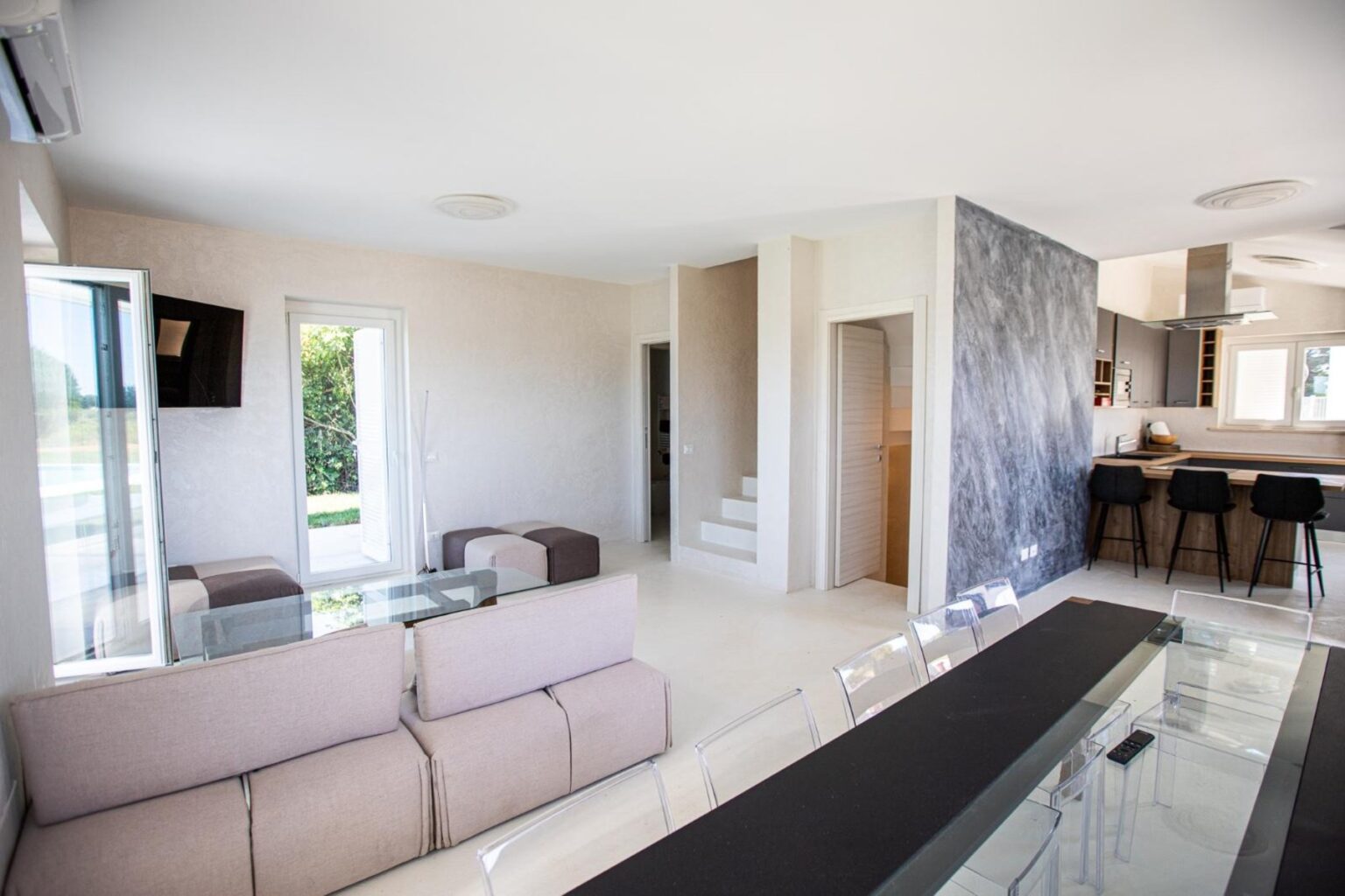 Modern open-concept living room and dining area with stylish furniture, large windows, and a contemporary kitchen in a bright, airy home. | Only on SopranoVillas
