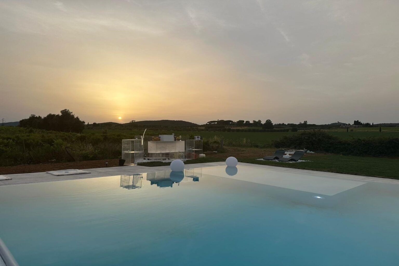 Sunset view from a luxury infinity pool overlooking lush green hills, creating a serene and tranquil atmosphere. | Only on SopranoVillas