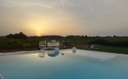 Sunset view from a luxury infinity pool overlooking lush green hills, creating a serene and tranquil atmosphere.