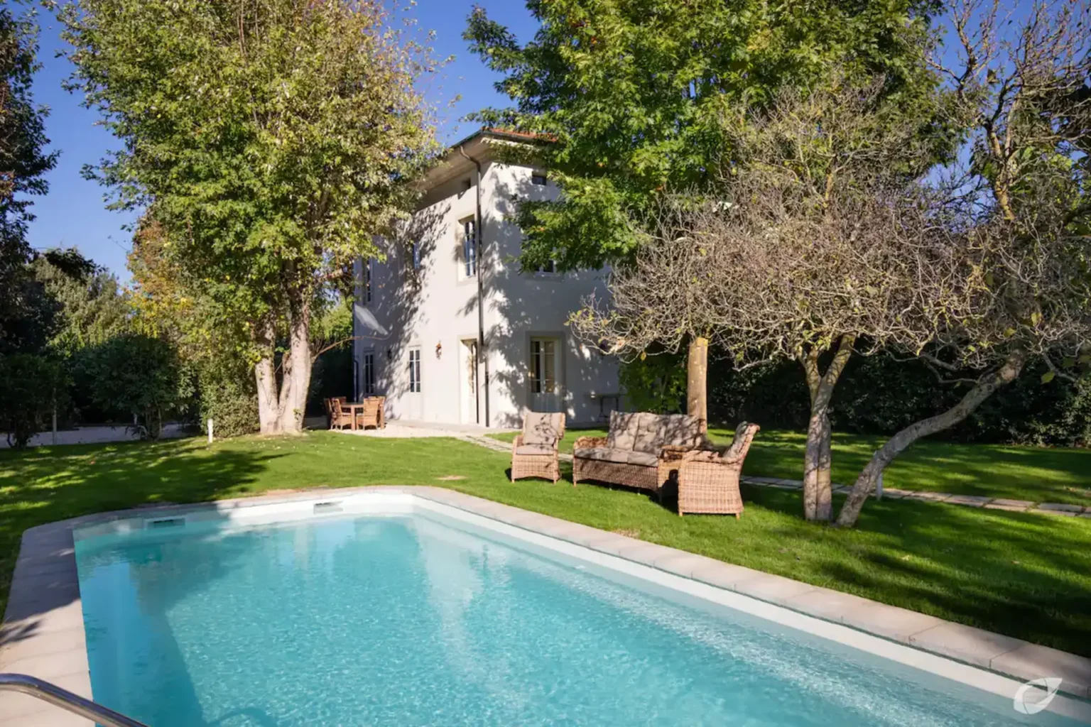 Modern house with a swimming pool surrounded by lush greenery and outdoor seating, ideal for relaxation and entertaining in a serene backyard setting. | Only on SopranoVillas