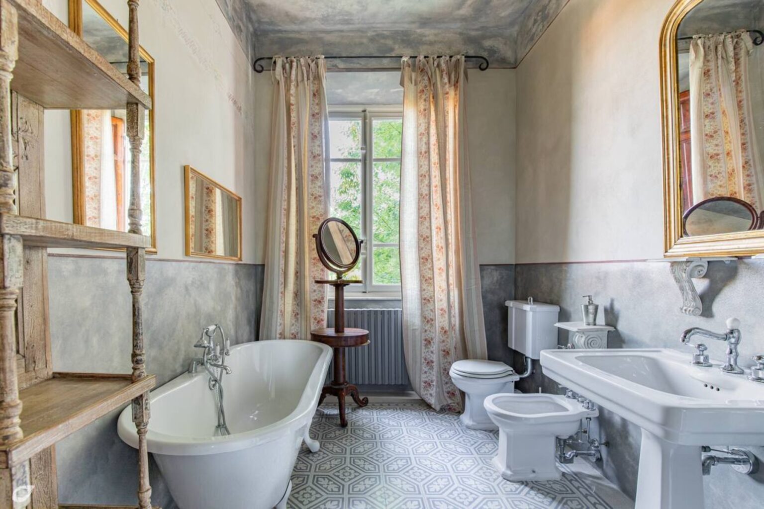 Elegant vintage bathroom featuring a freestanding bathtub, classic sink, and toilet, adorned with decorative mirrors and soft curtains, showcasing a blend of traditional and modern design elements. | Only on SopranoVillas