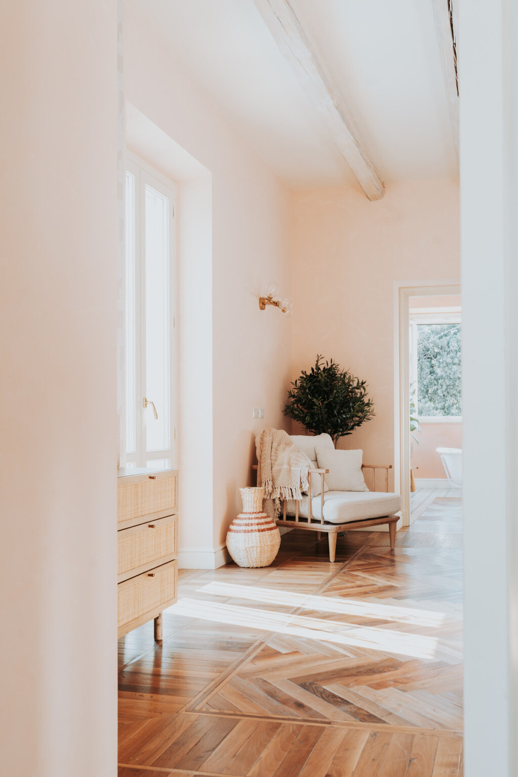 Cozy hallway featuring a light pink wall, a comfortable chair with decorative pillows, a small indoor plant, and natural light coming through a nearby window. | Only on SopranoVillas