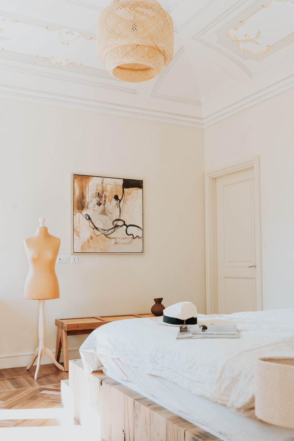 A stylish interior featuring a mannequin, an abstract painting in warm tones on the wall, and a wooden vase, creating a modern and inviting atmosphere. | Only on SopranoVillas