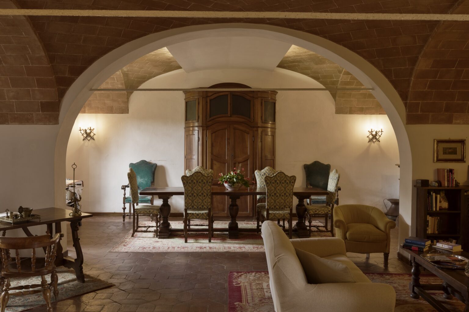Elegant interior of a dining area featuring a wooden table surrounded by stylish chairs, soft lighting, and arched architecture, creating a warm and inviting atmosphere. | Only on SopranoVillas