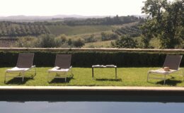 Relaxing outdoor setting with three lounge chairs beside a swimming pool, overlooking lush vineyards and rolling hills in the background. Ideal for a tranquil getaway or vacation retreat.