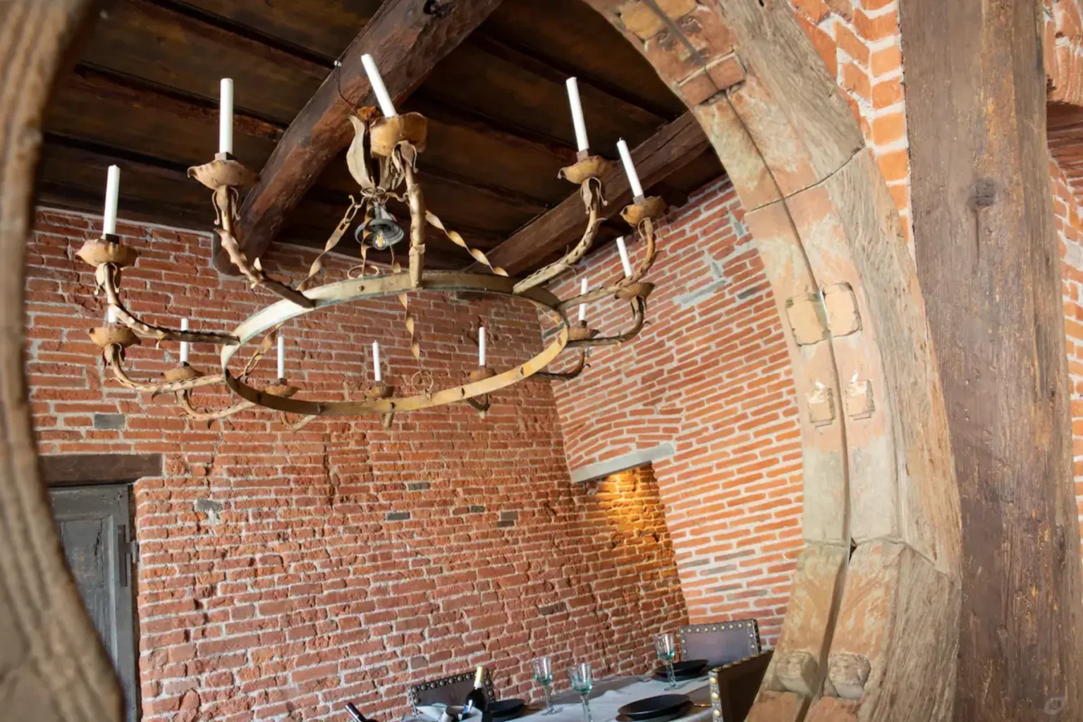 Rustic dining room featuring a vintage chandelier, exposed brick walls, and wooden beams, creating a cozy and inviting atmosphere. | Only on SopranoVillas
