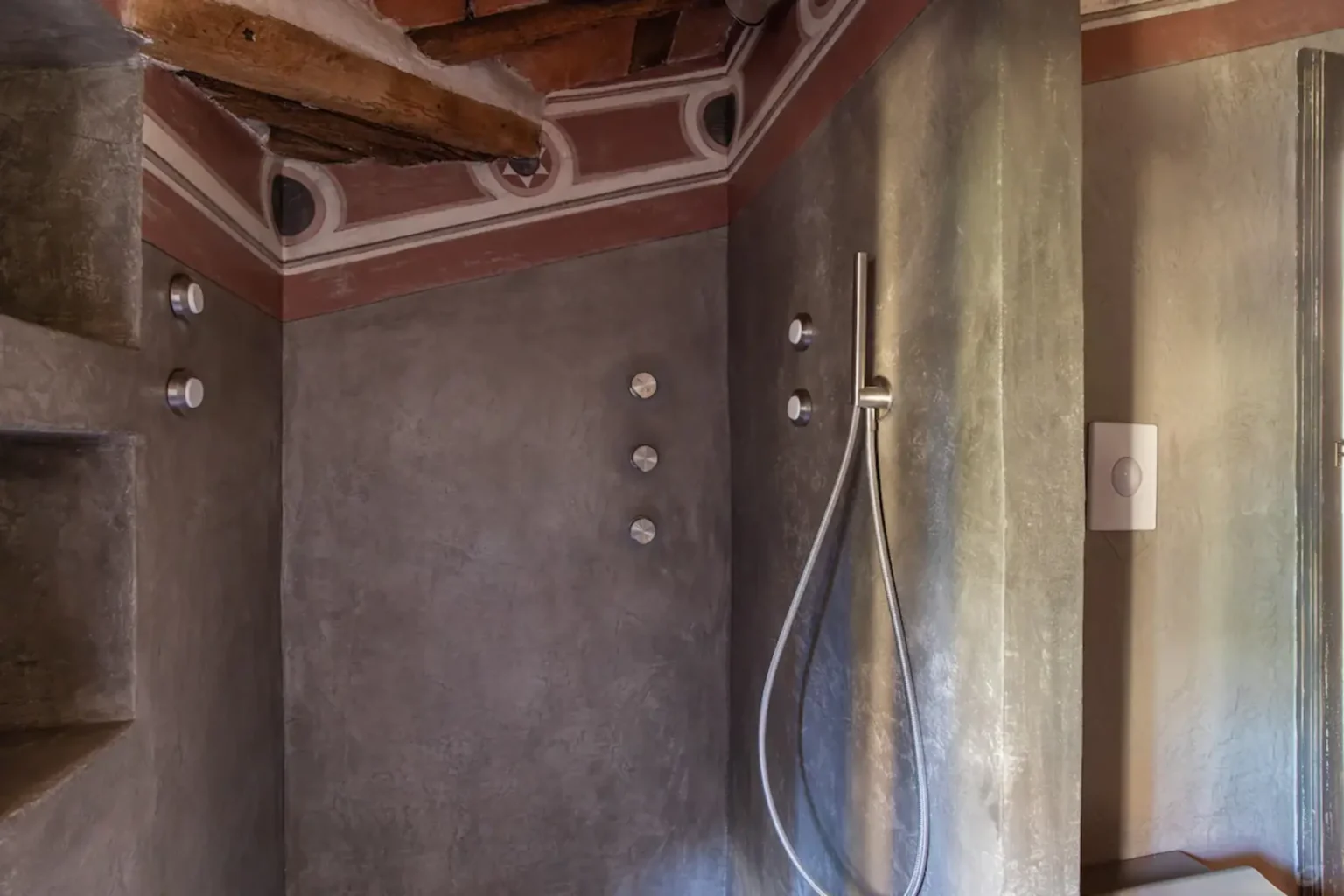 Modern bathroom design featuring a minimalist shower area with exposed beams, textured walls, and sleek fixtures. The space combines rustic and contemporary elements, creating a unique aesthetic. | Only on SopranoVillas