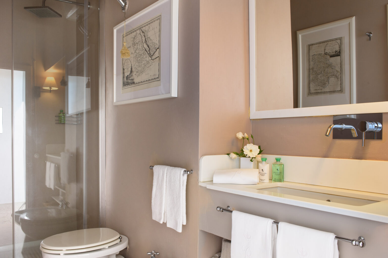 Modern bathroom featuring a glass shower enclosure, sleek sink with toiletries, and decorative wall art, showcasing a clean and stylish design. | Only on SopranoVillas