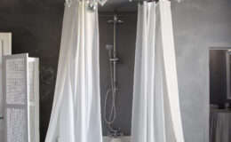 Modern bathroom design featuring a sleek shower area with white curtains, a contemporary showerhead, and a minimalist aesthetic against a dark gray wall.