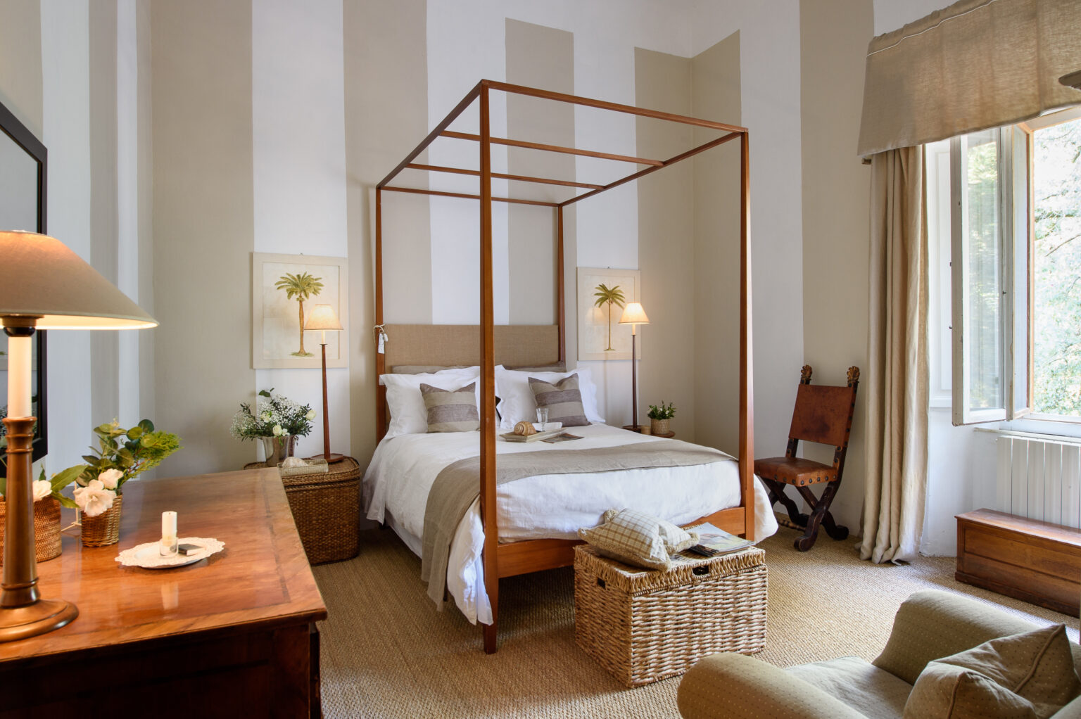 Elegant bedroom featuring a wooden four-poster bed, soft bedding, and neutral decor. The room includes a wooden dresser, a cozy chair, and natural light streaming through large windows, creating a serene atmosphere. | Only on SopranoVillas
