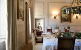 Elegant dining room featuring a beautifully set table with fine china, surrounded by tasteful decor and artwork. Natural light floods the space, highlighting the sophisticated ambiance and inviting atmosphere.