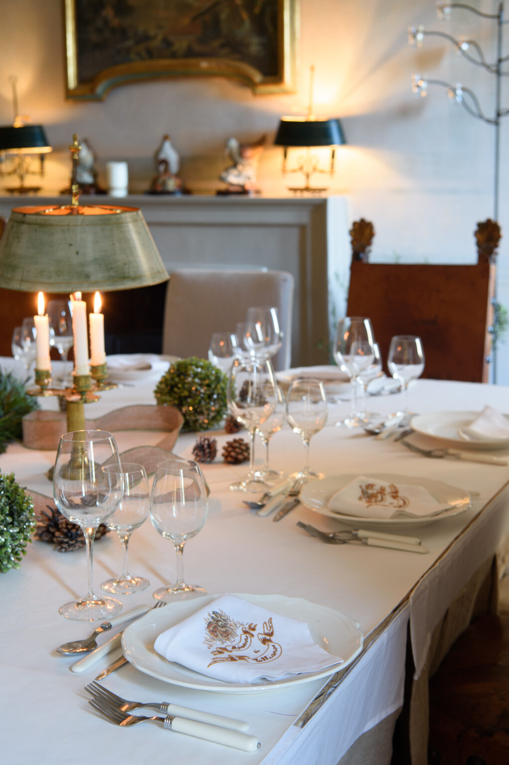 Elegant dining table set for a festive meal, featuring candles, wine glasses, and decorative elements like pinecones and greenery, creating a warm and inviting atmosphere. | Only on SopranoVillas