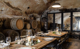 Rustic dining room in a wine cellar featuring wooden barrels, elegant table settings, and soft lighting, ideal for intimate gatherings or wine tastings.