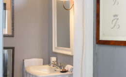 Modern bathroom interior featuring a white sink, elegant wall mirrors, soft lighting, and a neutral gray color scheme, ideal for home decor inspiration.