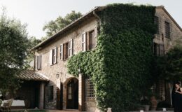Stone house covered in ivy with wooden shutters, surrounded by greenery, set in a tranquil outdoor environment. Ideal for rustic charm and nature-inspired architecture.