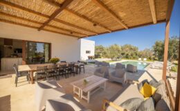 Modern outdoor patio with comfortable seating, dining area, and swimming pool in a sunny landscape. Ideal for relaxation and entertaining guests.
