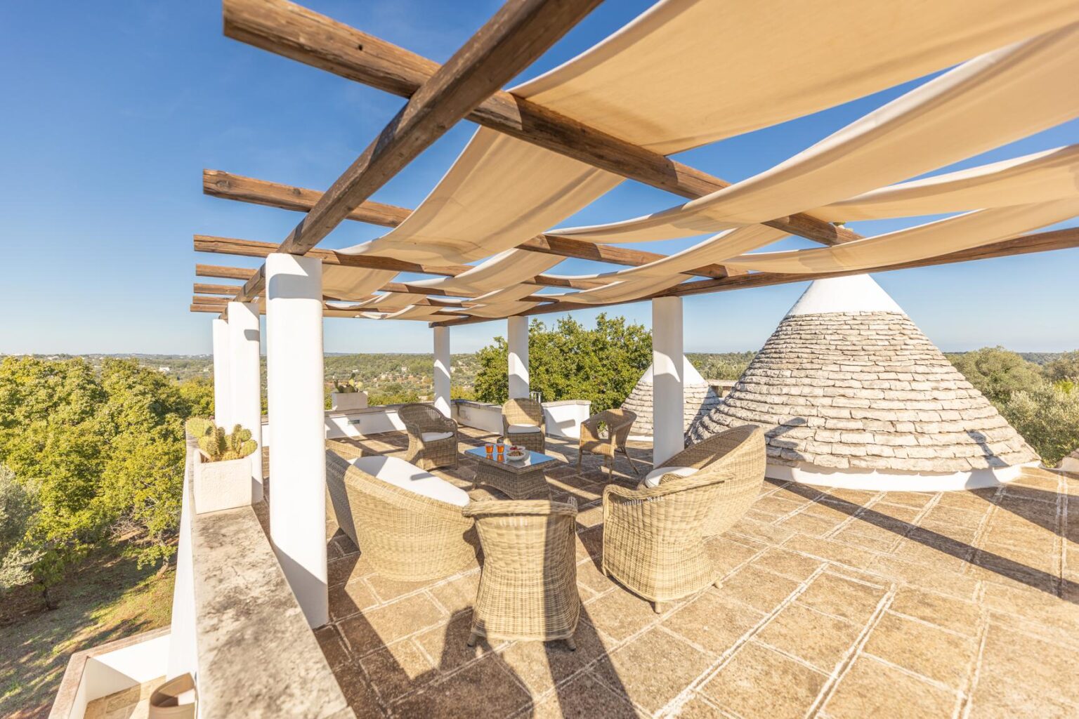Spacious outdoor terrace with wooden beams and fabric canopies, featuring comfortable seating and scenic views of the surrounding landscape. Perfect for relaxation and entertaining in a serene setting. | Only on SopranoVillas