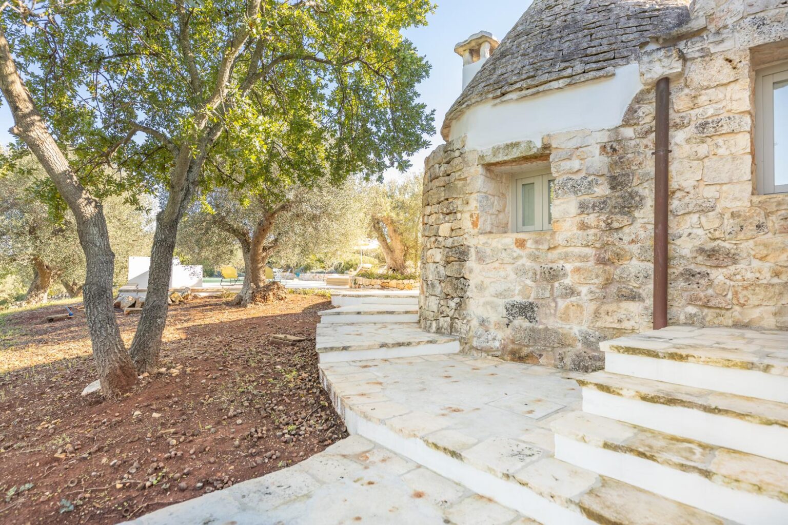Stone cottage with a curved pathway and surrounding trees, showcasing a tranquil outdoor setting. | Only on SopranoVillas