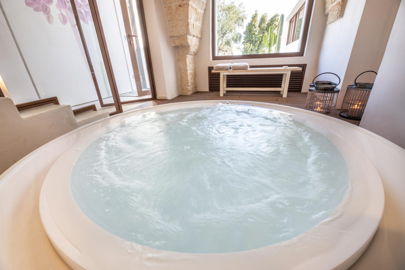 Luxurious indoor jacuzzi with bubbling water, surrounded by large windows and natural light, creating a serene spa-like atmosphere. | Only on SopranoVillas