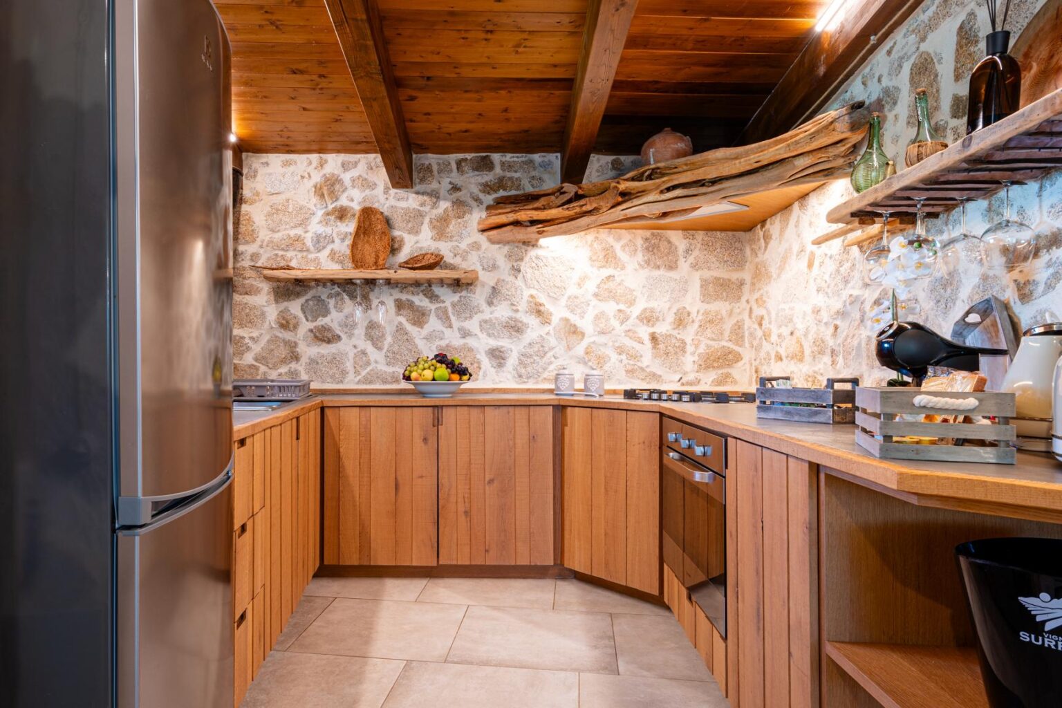 Modern rustic kitchen featuring stone walls, wooden cabinetry, and open shelving, designed for functionality and style. | Only on SopranoVillas