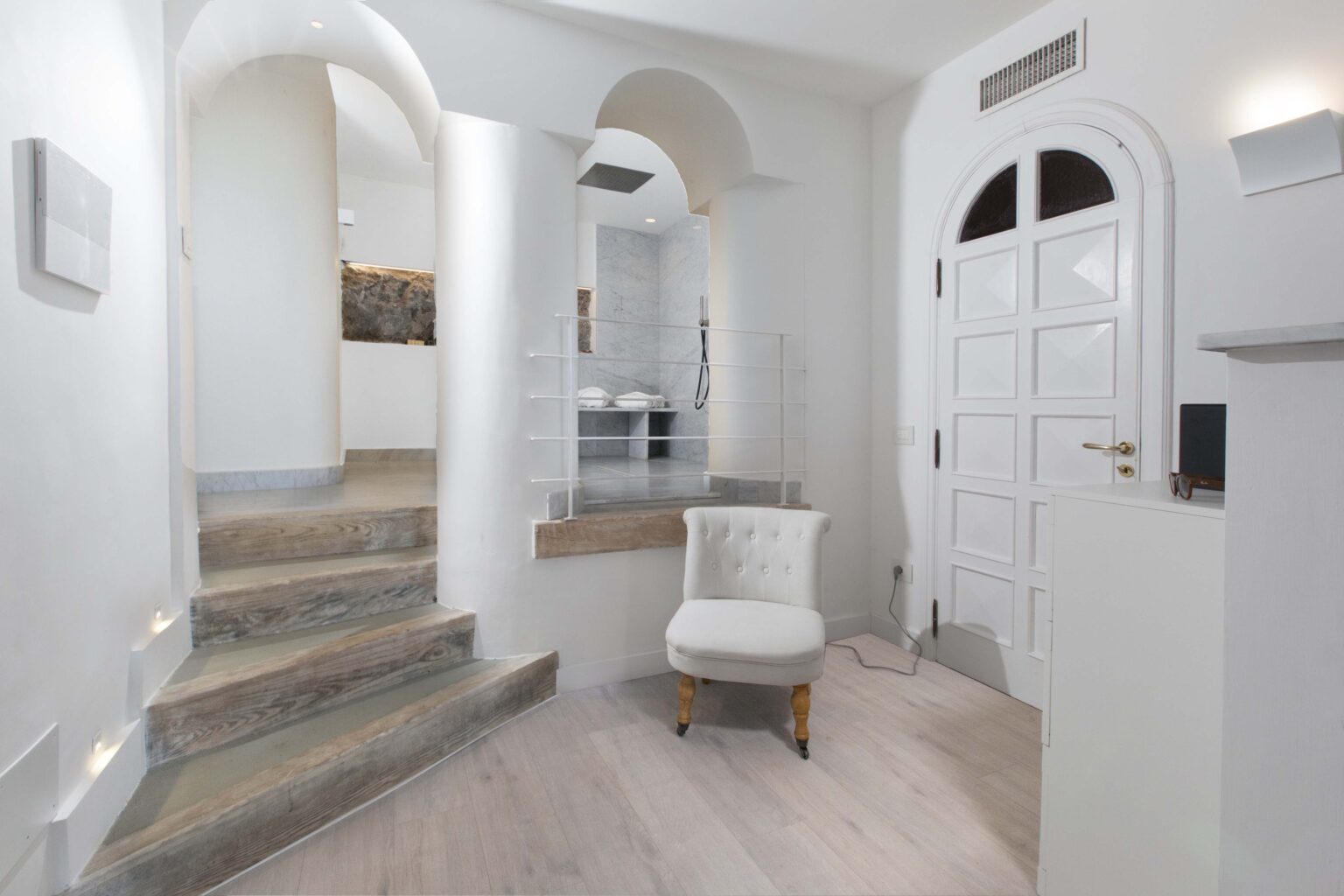 Modern entryway featuring a staircase, white walls, and a stylish chair, creating a welcoming atmosphere in a contemporary home. | Only on SopranoVillas