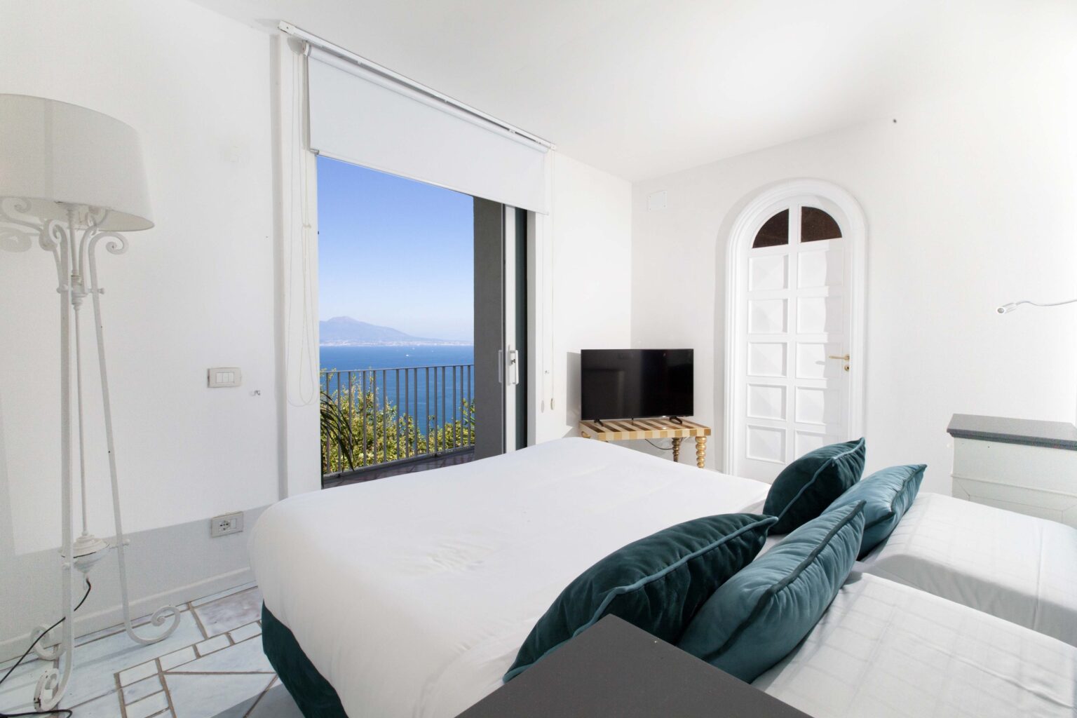 Bright and airy bedroom with a stunning sea view, featuring a large window, modern furnishings, a television, and a cozy ambiance, perfect for relaxation. | Only on SopranoVillas