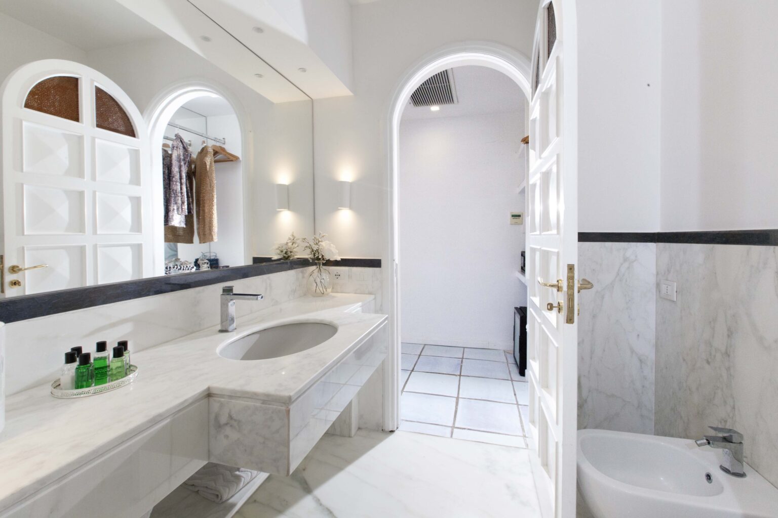 Modern bathroom with marble countertops, stylish sink, and elegant lighting, featuring arched doorways and a clean, minimalist design. | Only on SopranoVillas