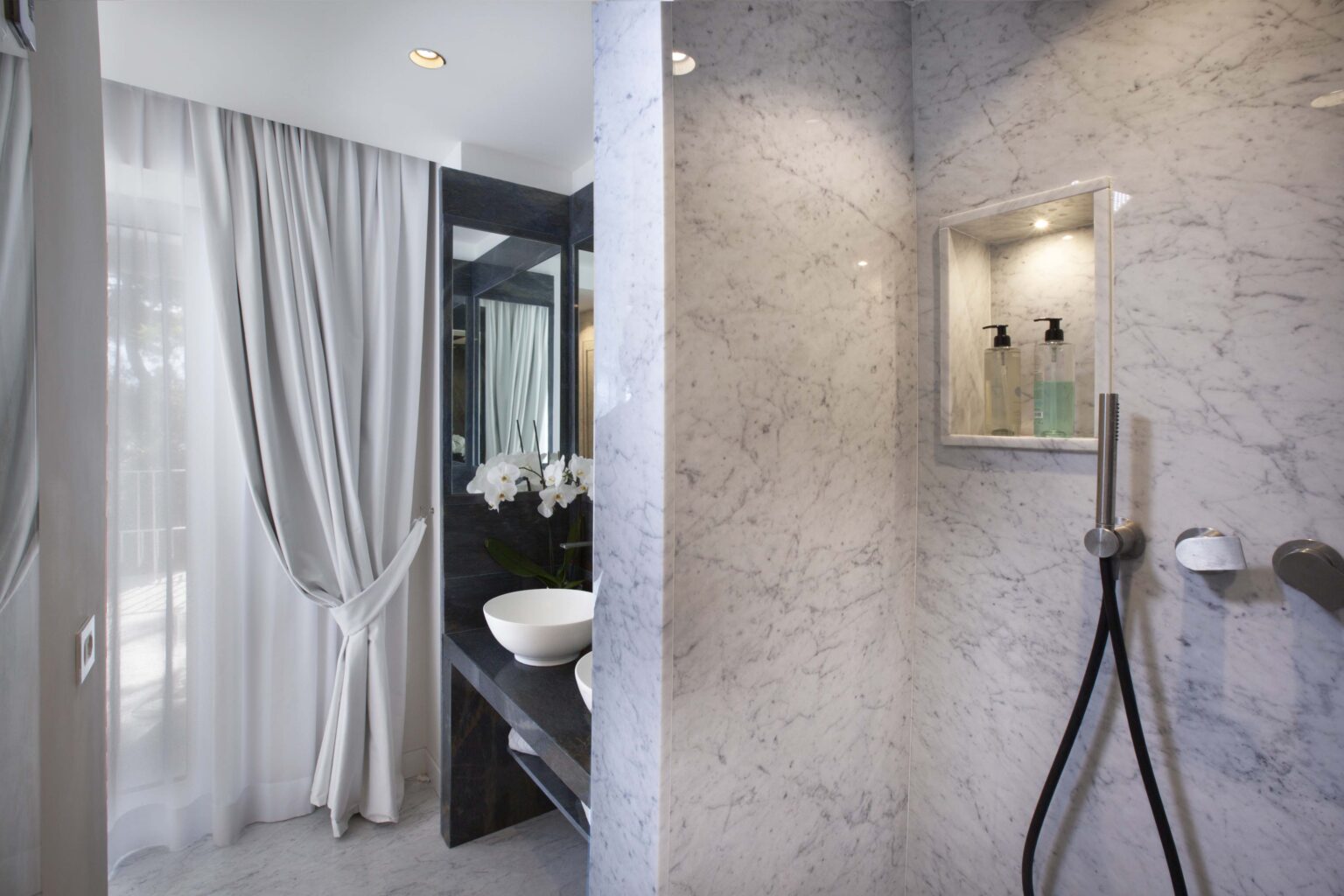 Modern bathroom featuring a stylish shower area with marble walls, a sleek sink, and elegant curtains, creating a luxurious and serene atmosphere. | Only on SopranoVillas