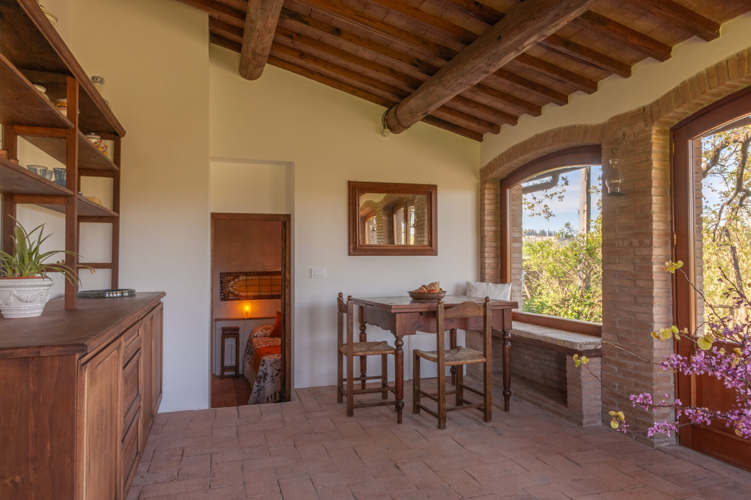 Cozy interior of a rustic dining area featuring wooden beams, a table with chairs, and large windows showcasing a scenic view, perfect for enjoying meals in a warm atmosphere. | Only on SopranoVillas