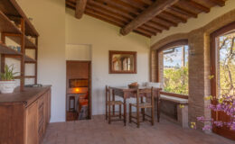 Cozy interior of a rustic dining area featuring wooden beams, a table with chairs, and large windows showcasing a scenic view, perfect for enjoying meals in a warm atmosphere.