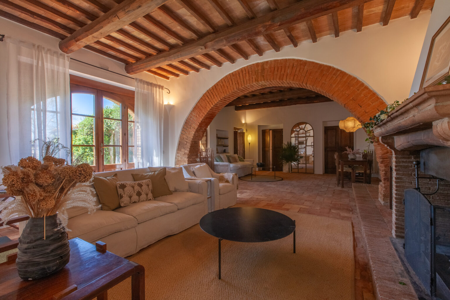 Cozy living room featuring arched ceilings, large windows with natural light, a comfortable sofa, and a stylish coffee table, creating an inviting atmosphere in a rustic home setting. | Only on SopranoVillas
